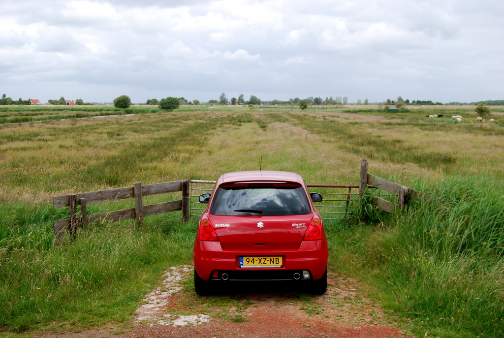 Red car parked at gate to paddock in Zaanse Schans, Netherlands