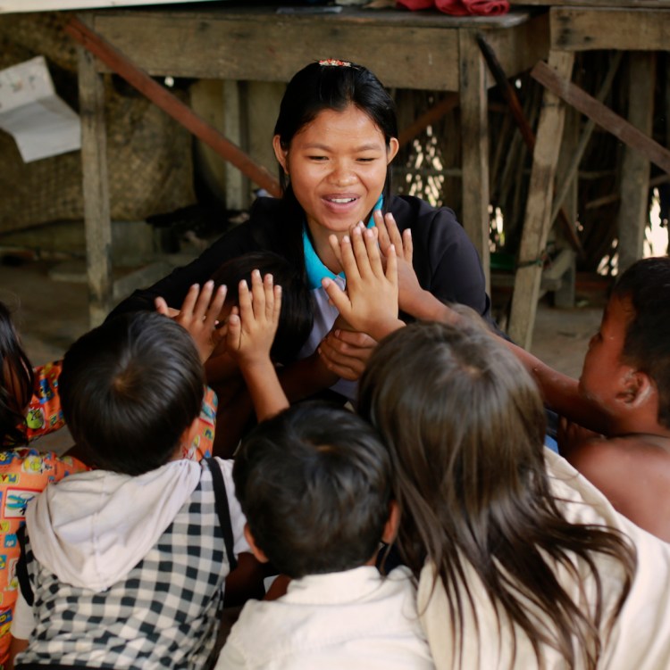 Disability worker Chhean high-fives children in the home of a child who receives speech therapy (Photo: Mona Simon/OIC: The Cambodia Project) 